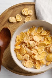Photo of Tasty cornflakes with milk in bowl served on white table, top view