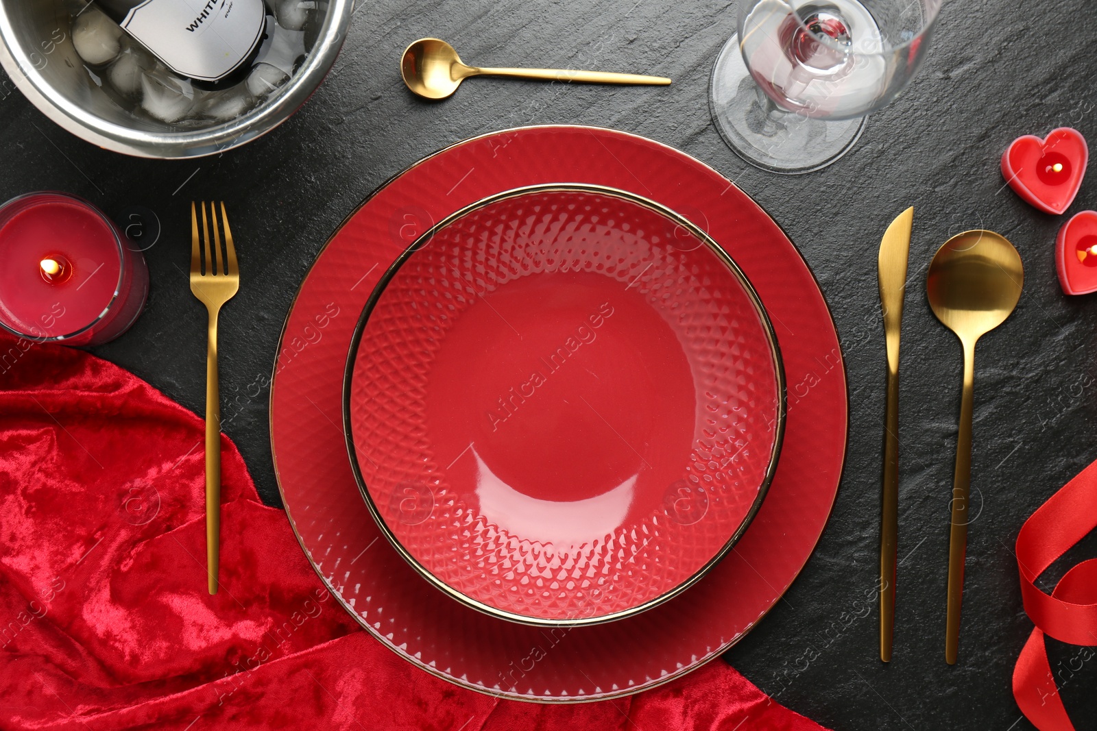 Photo of Romantic place setting with candles on dark gray textured table, flat lay