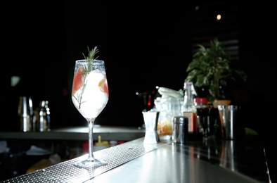 Photo of Fresh alcoholic grapefruit and rosemary gin tonic cocktail on bar counter. Space for text