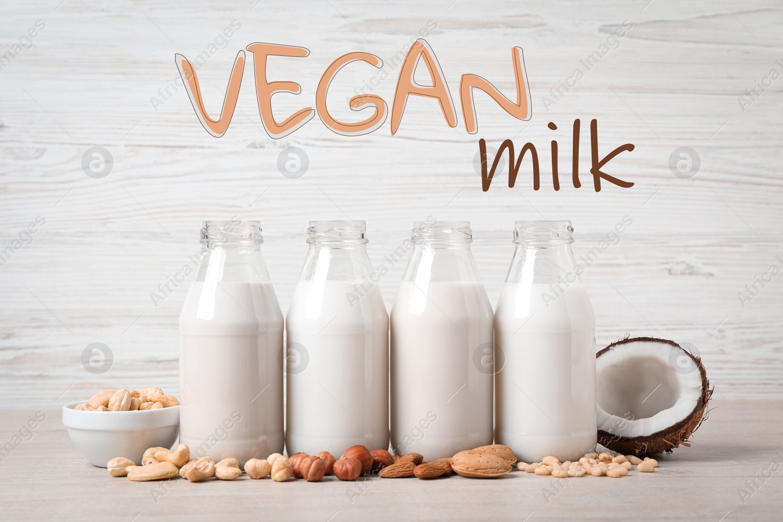 Image of Different vegan milks in glass bottles and nuts on white table