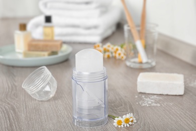 Photo of Natural crystal alum deodorant and chamomile flowers on wooden table
