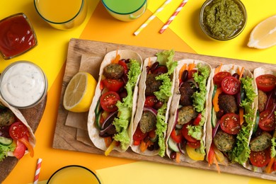 Photo of Many delicious vegetarian tacos served on yellow table , flat lay