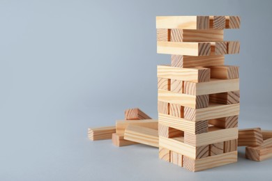Photo of Jenga tower made of wooden blocks on grey background, space for text