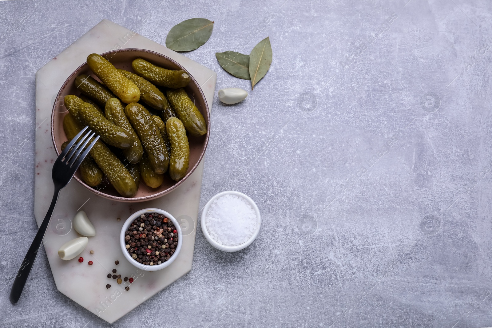 Photo of Fork with bowl of pickled cucumbers and ingredients on light grey table, flat lay. Space for text