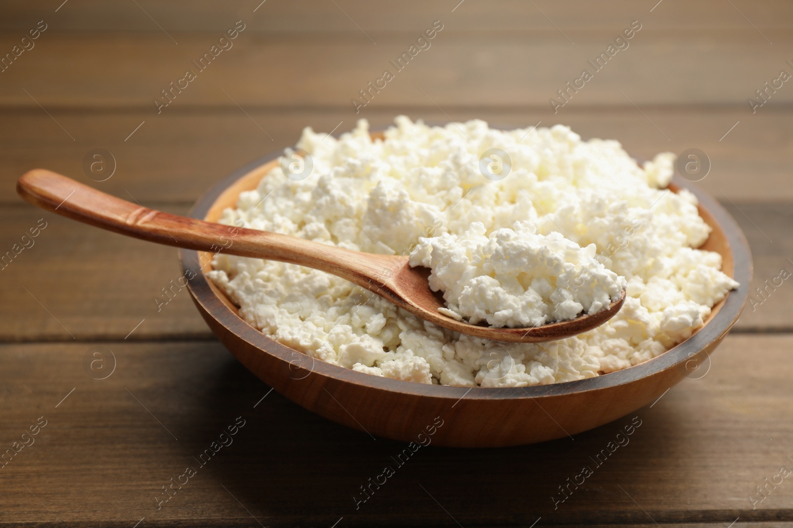 Photo of Delicious fresh cottage cheese on wooden table, closeup