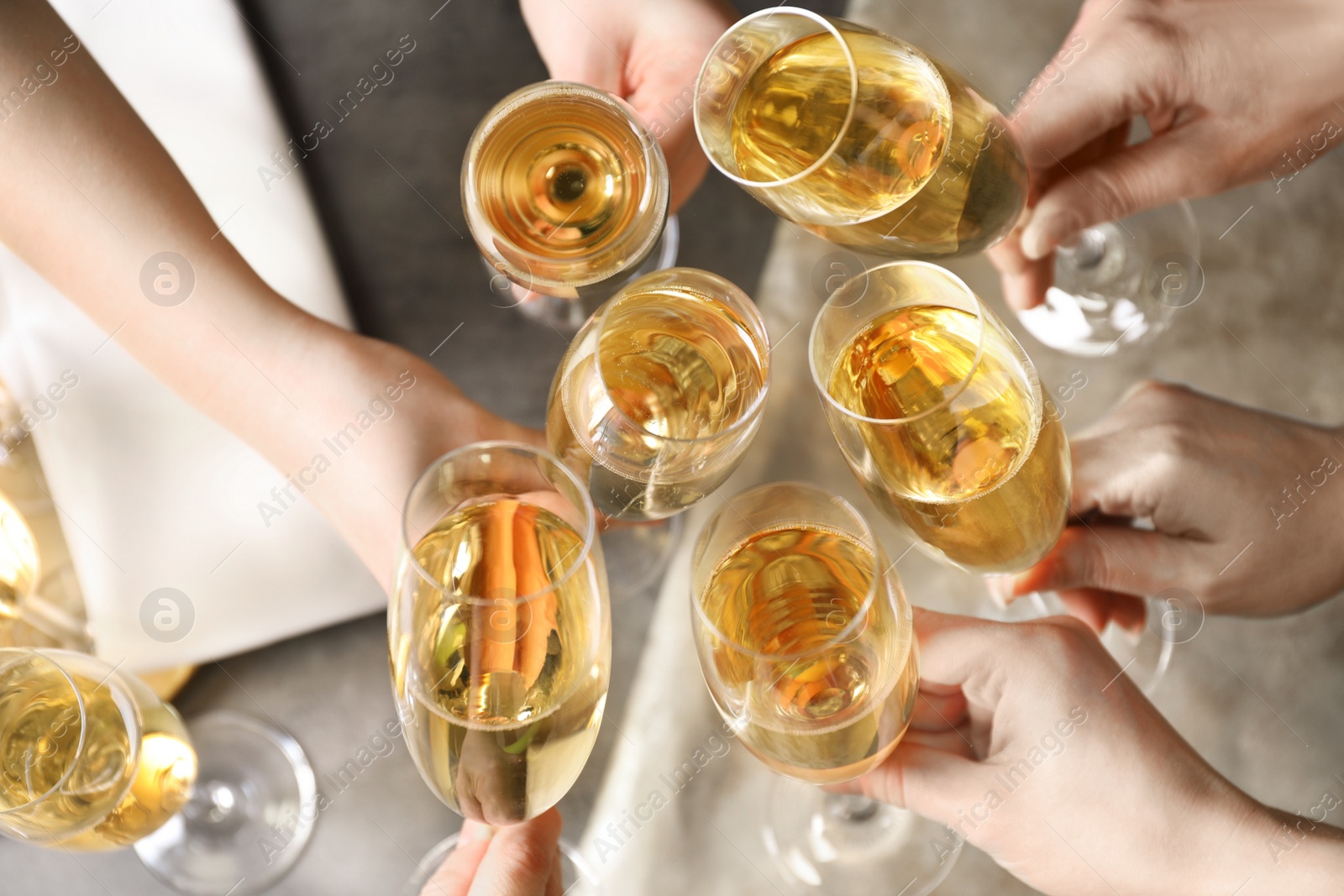 Photo of People clinking glasses with champagne over table, top view