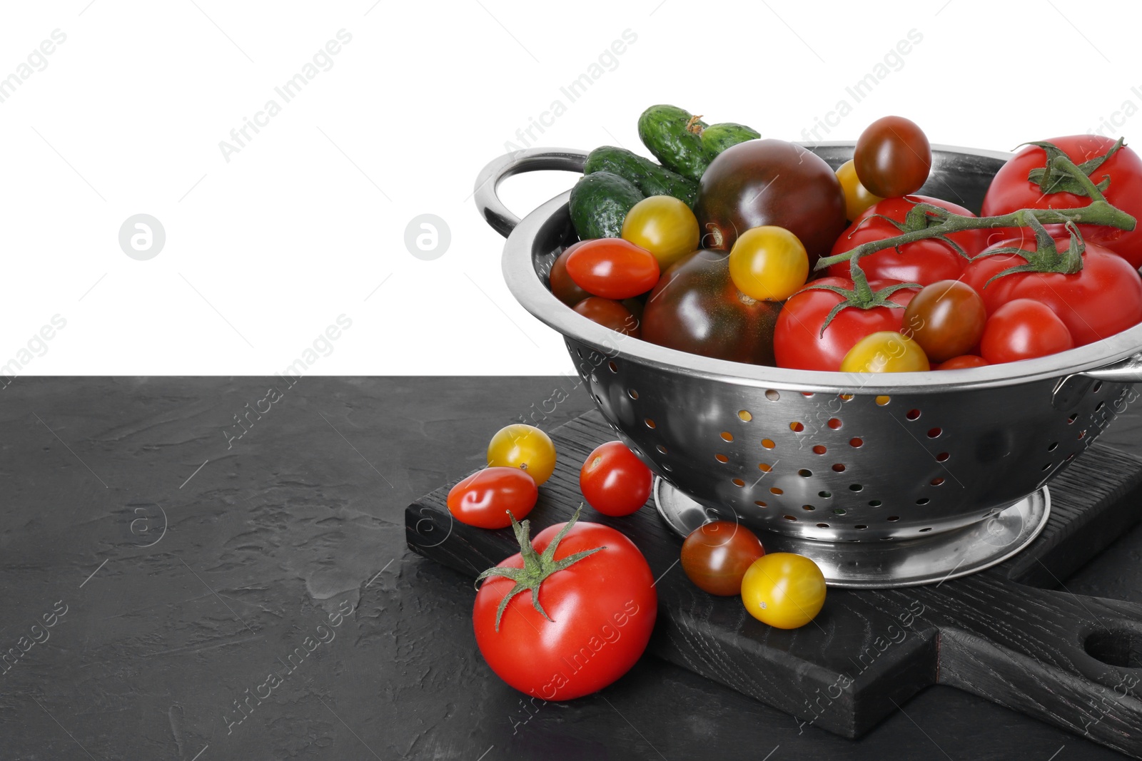 Photo of Metal colander with fresh tomatoes on black textured table against white background, space for text