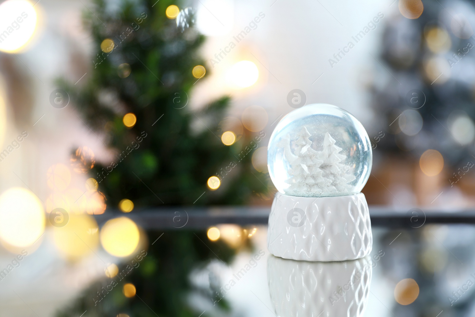 Photo of Decorative Christmas snow globe on mirror surface indoors