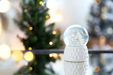 Photo of Decorative Christmas snow globe on mirror surface indoors