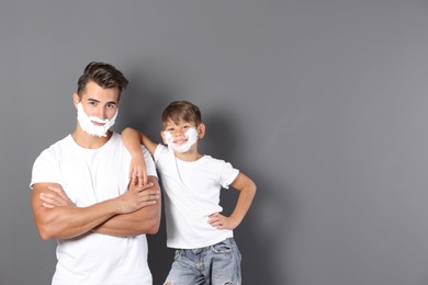 Photo of Father and son with shaving foam on faces against color background. Space for text