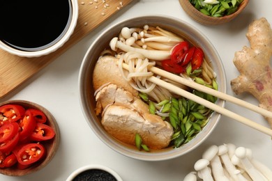 Delicious ramen with meat and ingredients on white marble table, flat lay. Noodle soup