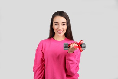 Photo of Woman with dumbbell as symbol of girl power on light grey background. 8 March concept