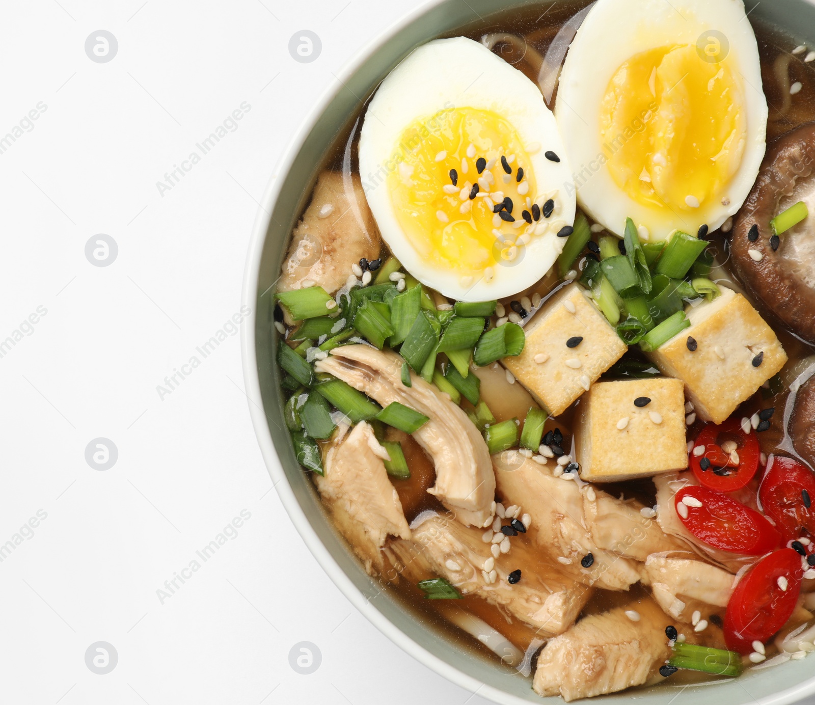 Photo of Bowl of delicious ramen isolated on white, top view. Noodle soup