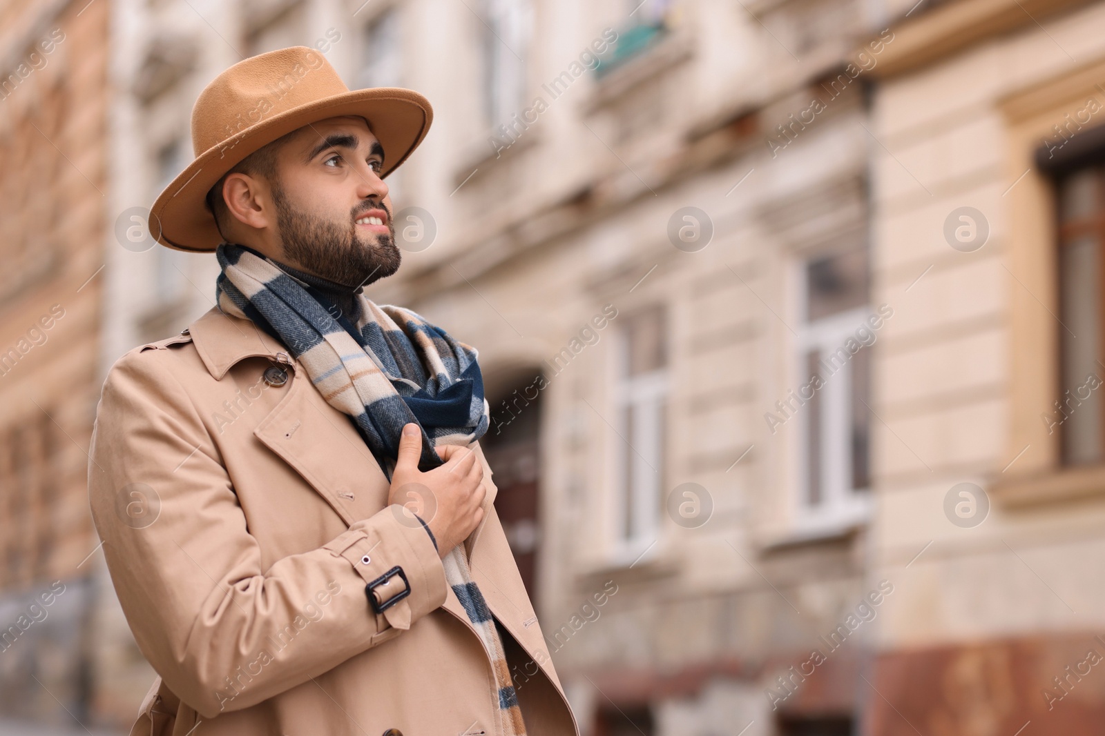 Photo of Handsome man in warm scarf on city street. Space for text