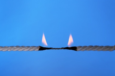 Burning rope at breaking point on color background