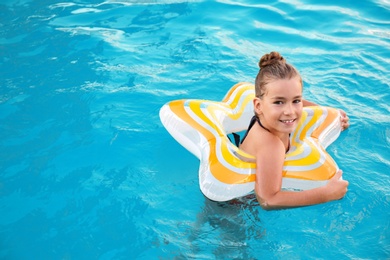 Photo of Happy little girl with inflatable ring in swimming pool