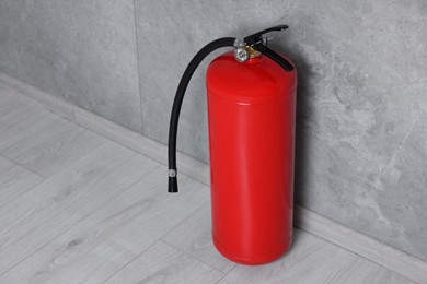 Fire extinguisher on floor near grey wall, space for text