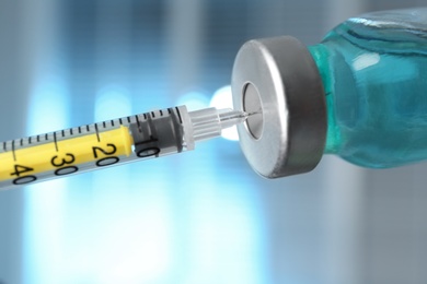 Filling syringe with medication from vial against blurred background, closeup. Vaccination and immunization