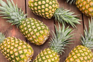 Photo of Delicious ripe pineapples on wooden table, flat lay