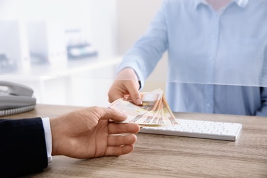 Photo of Man receiving money from teller at cash department window, closeup