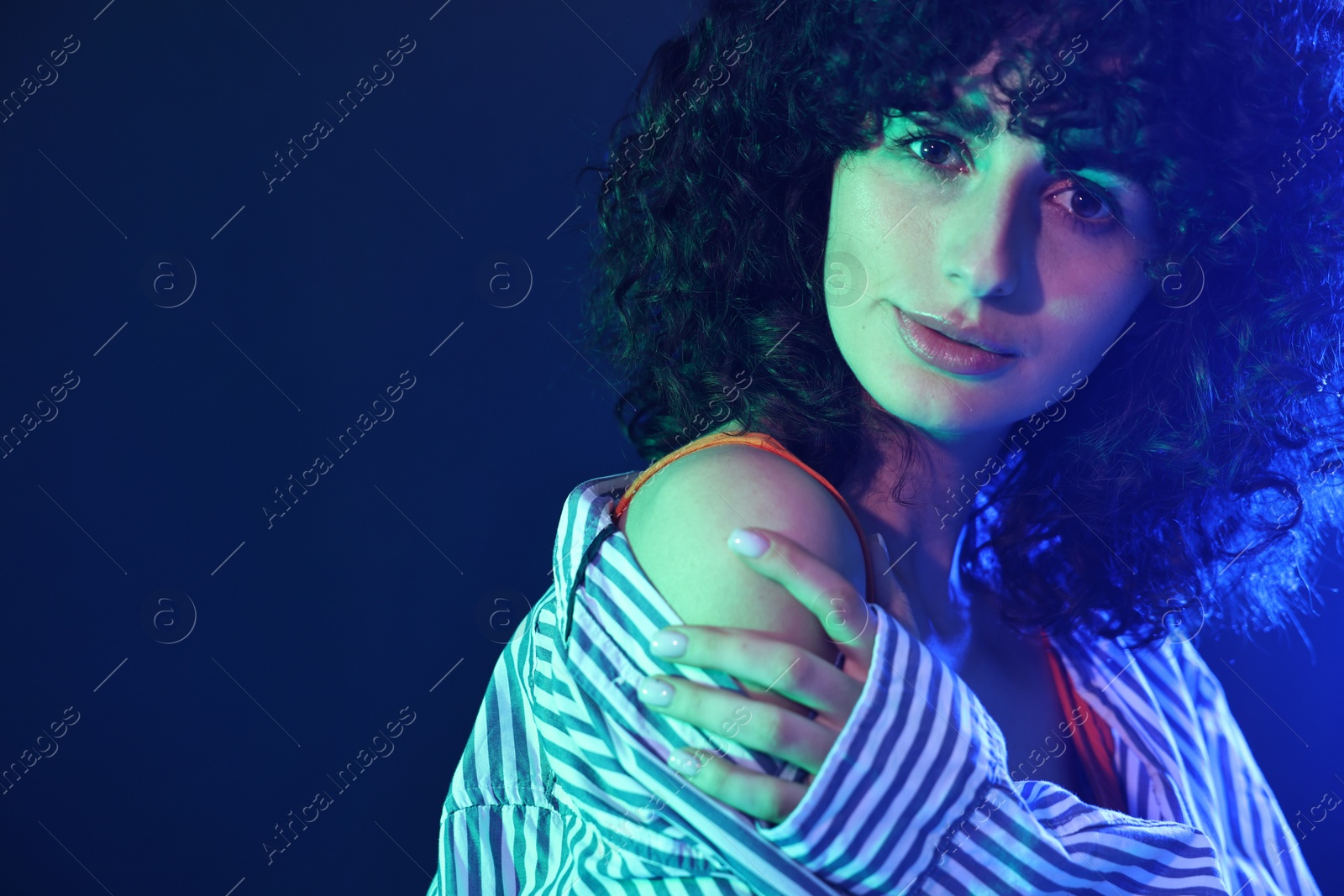 Photo of Beautiful young woman posing on color background in neon lights. Space for text