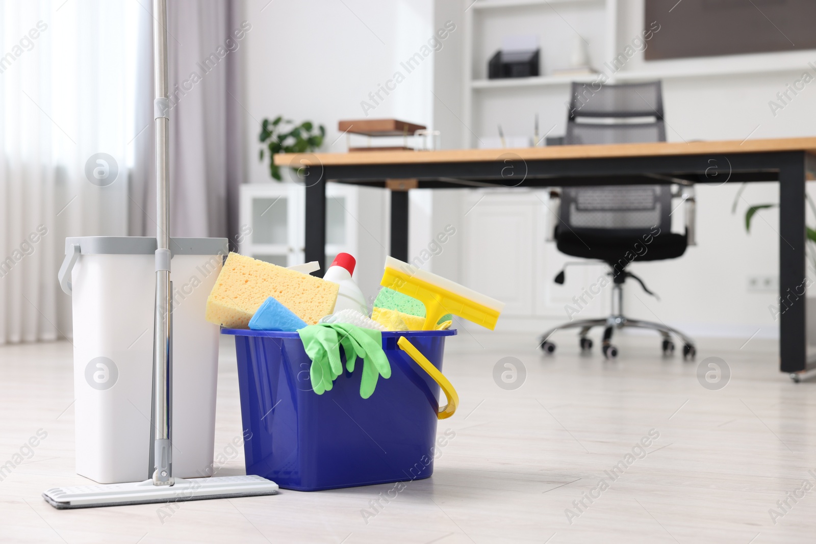 Photo of Cleaning service. Mop and bucket with supplies in office, space for text