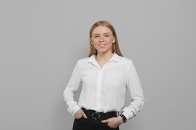 Portrait of beautiful young woman in white shirt on grey background