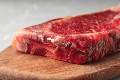 Photo of Raw beef meat on wooden board, closeup view