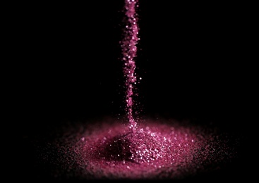 Sprinkling rose glitter on black background, bokeh effect