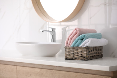 Photo of Basket with fresh towels on countertop in bathroom