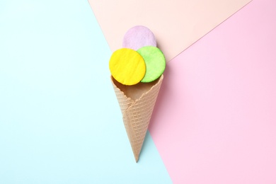 Wafer cone and dyed cotton pads as ice cream on color background, top view