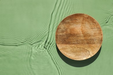 Photo of Presentation of product. Wooden podium in water on green background, top view. Space for text