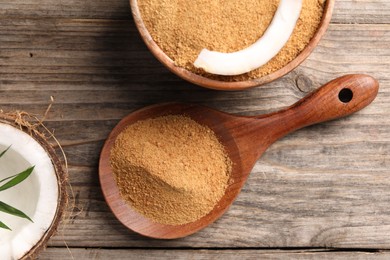 Photo of Coconut sugar in bowl, spoon and fruit on wooden table, flat lay