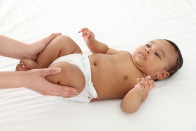 Photo of Mother and her cute child on white bed. Baby massage and exercises