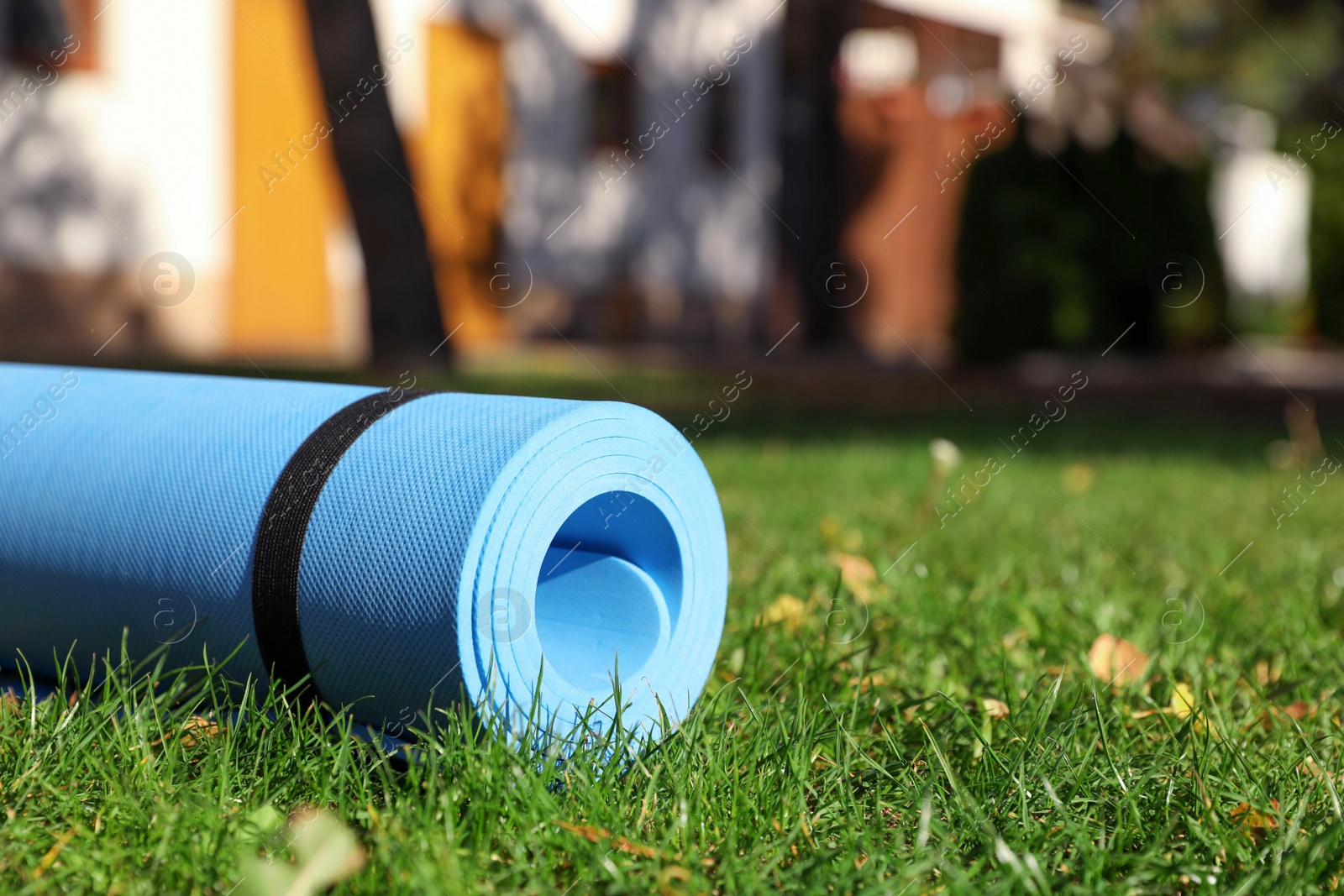 Photo of Blue karemat or fitness mat on fresh green grass in park, closeup. Space for text