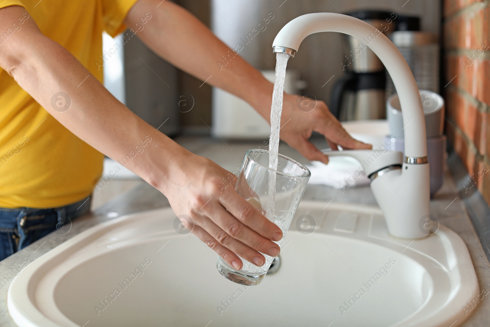 Photo of Woman filling glass with water from faucet in kitchen, closeup