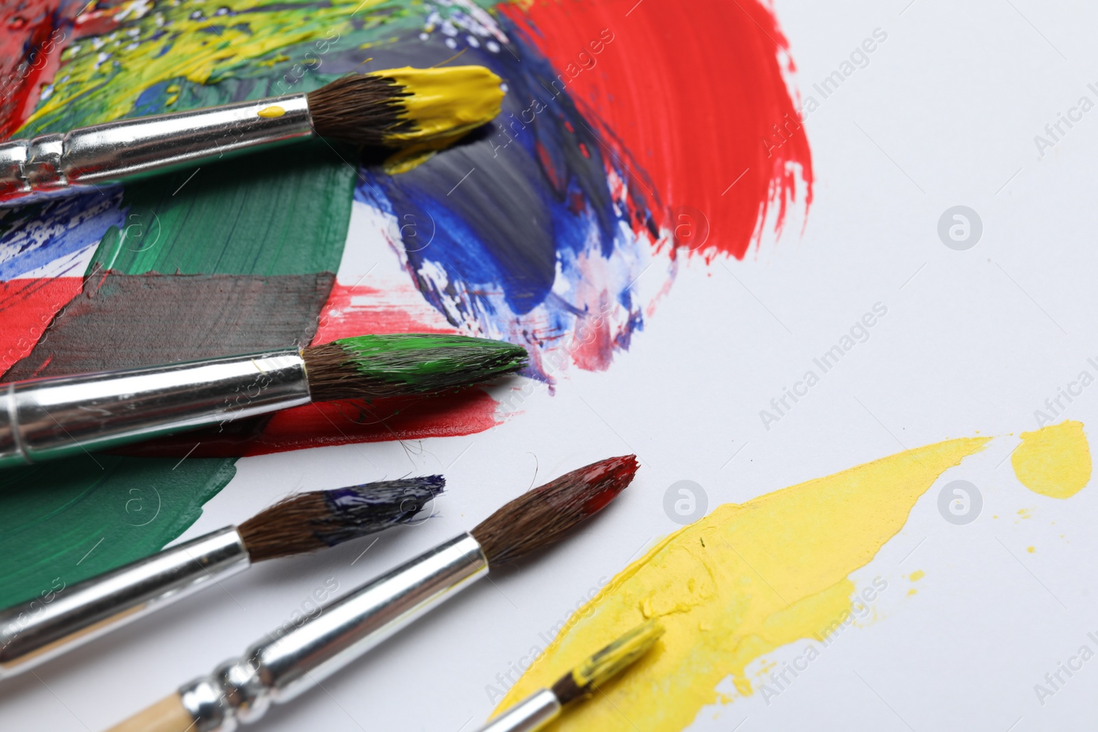Photo of Brushes with different paints and strokes on white background, closeup. Space for text