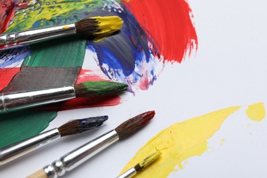 Brushes with different paints and strokes on white background, closeup. Space for text