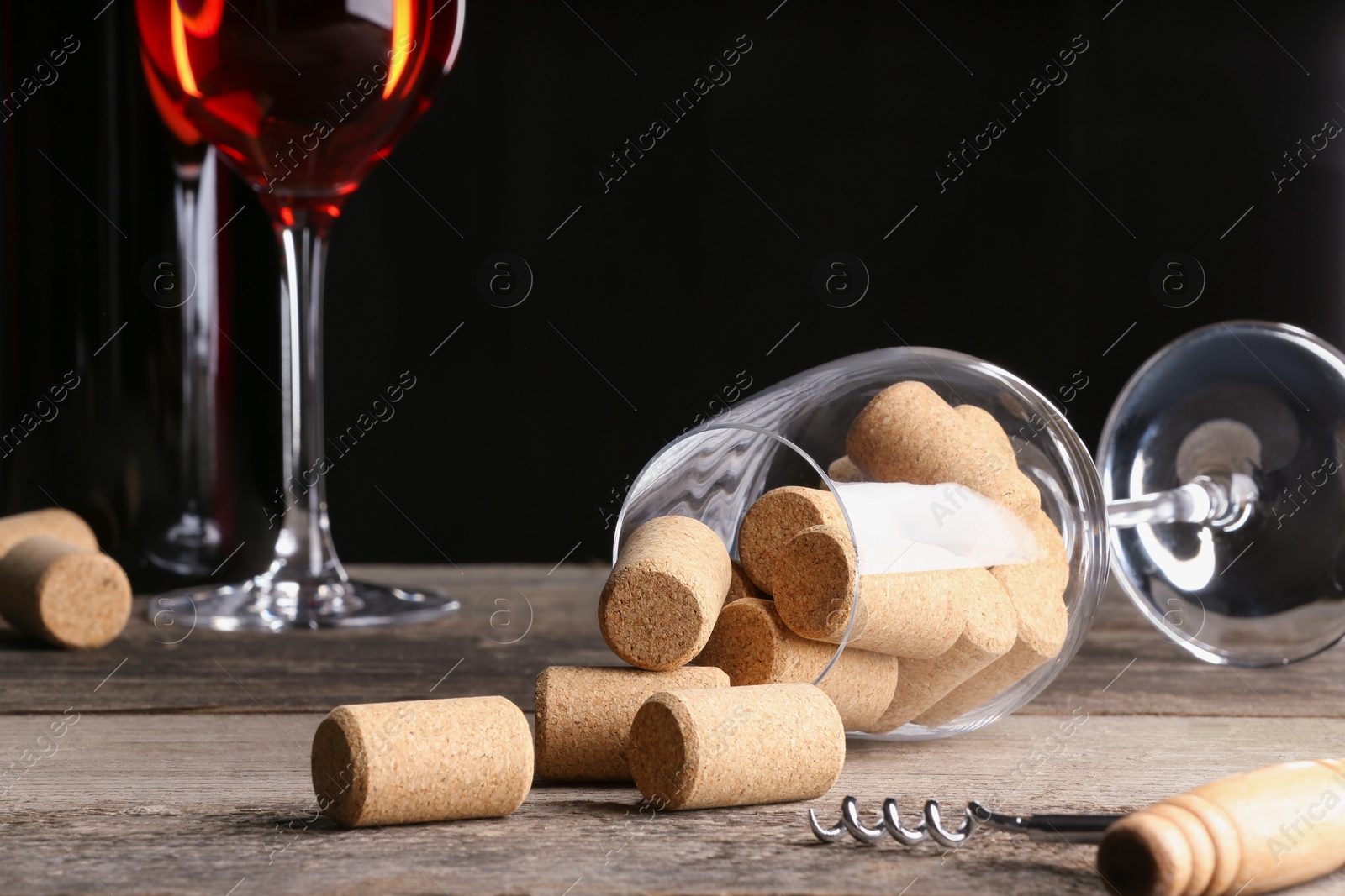 Photo of Glass with corks and corkscrew on wooden table