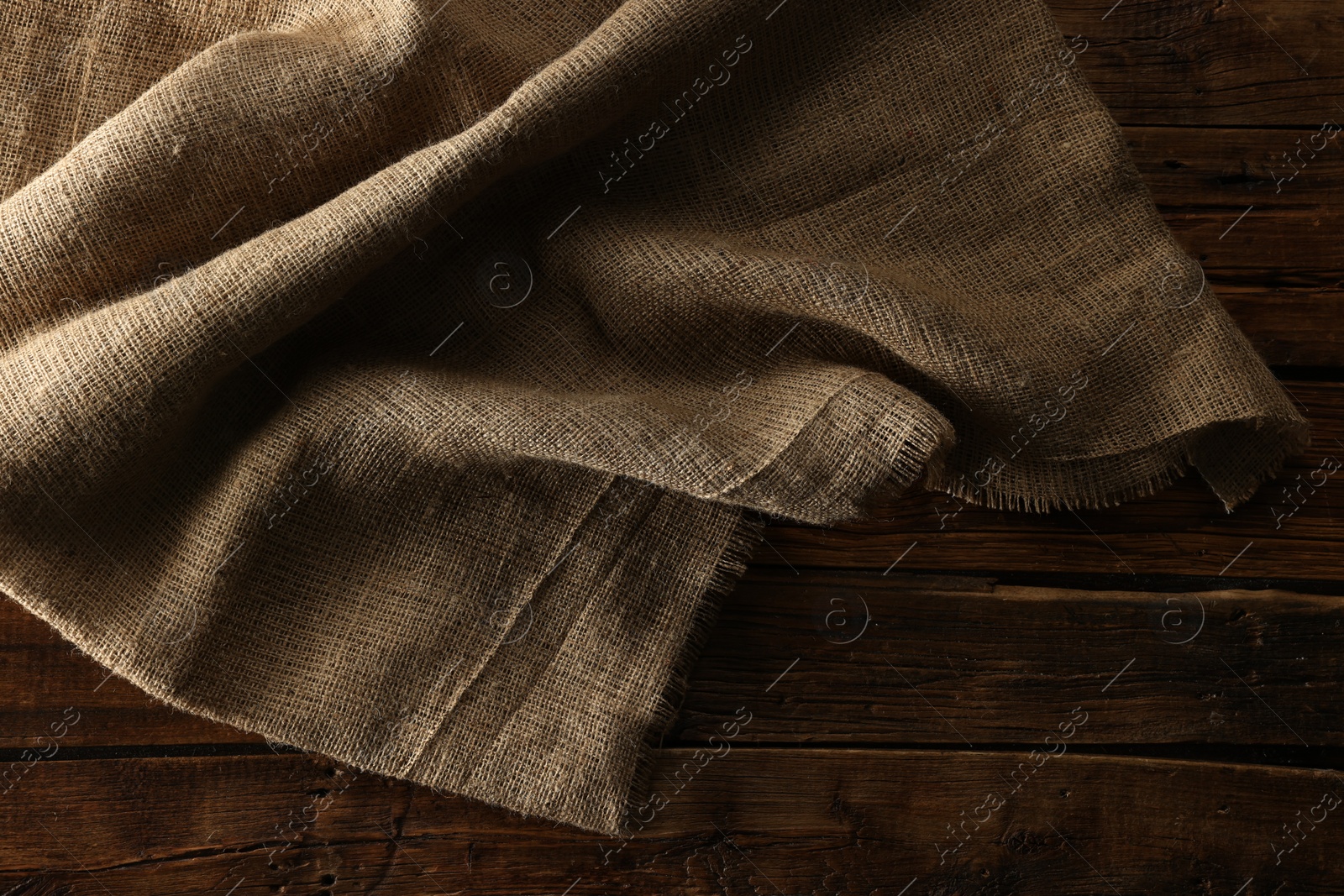 Photo of Burlap fabric on wooden table, top view