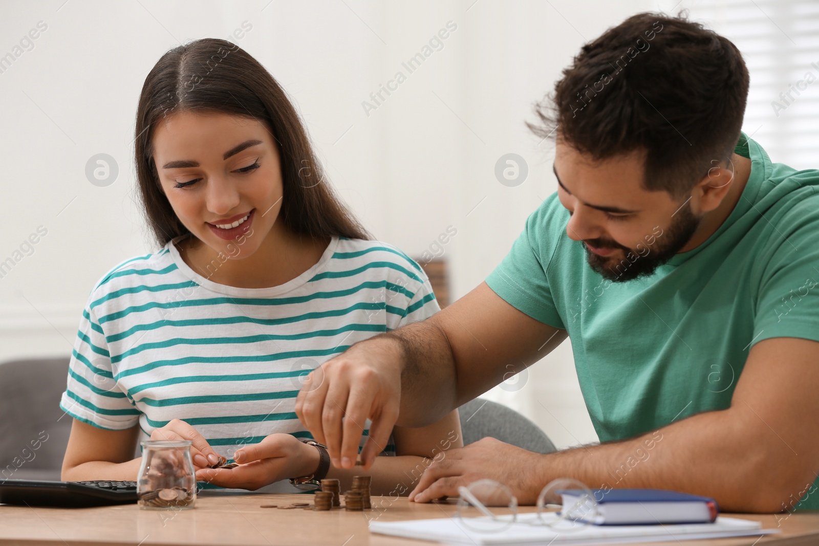 Photo of Happy young couple counting money at wooden table indoors