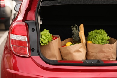 Photo of Bags full of groceries in car trunk outdoors, closeup