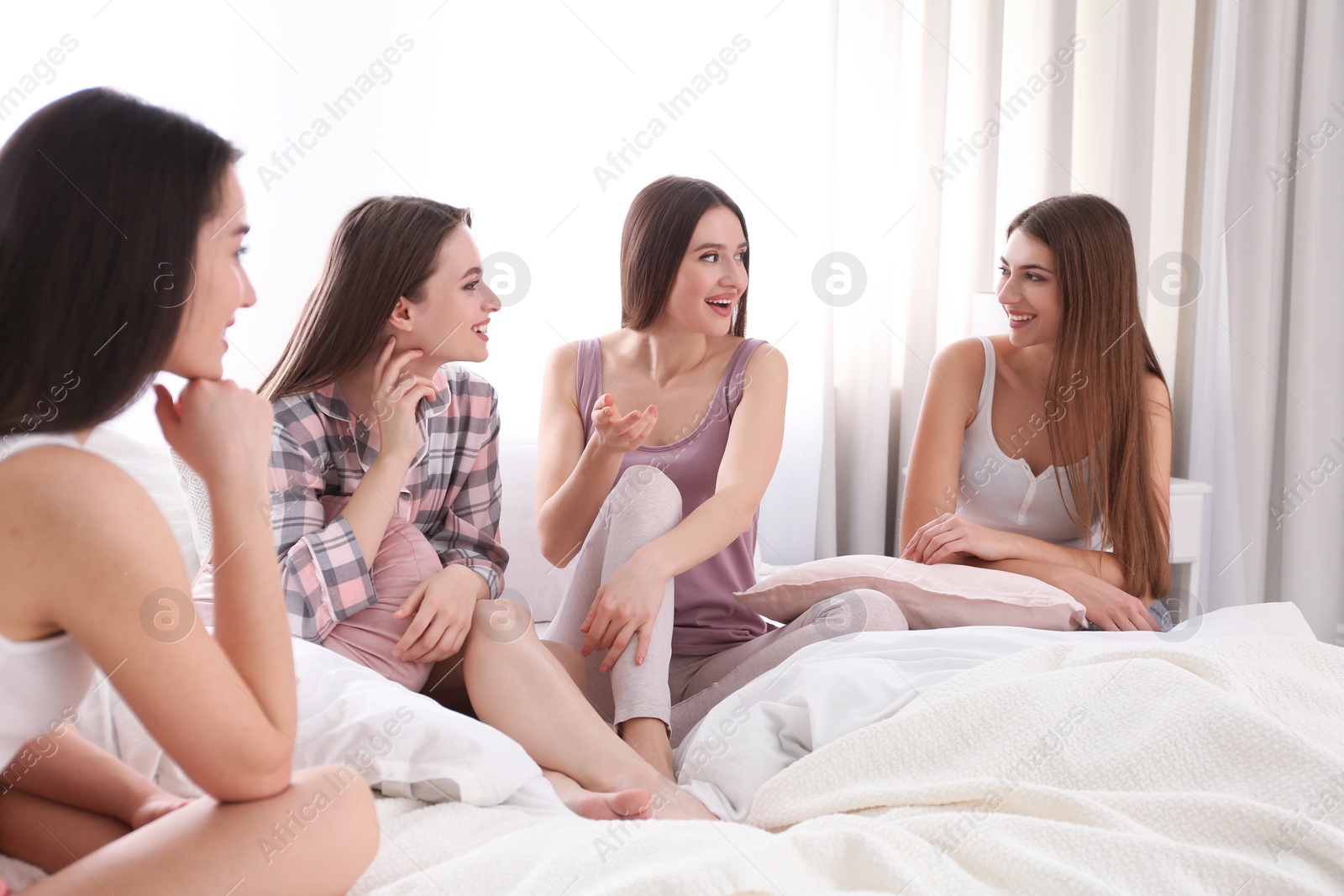 Photo of Beautiful young ladies on bed at pamper party. Woman's Day