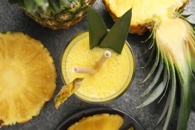 Tasty pineapple smoothie and fruit on grey table, flat lay