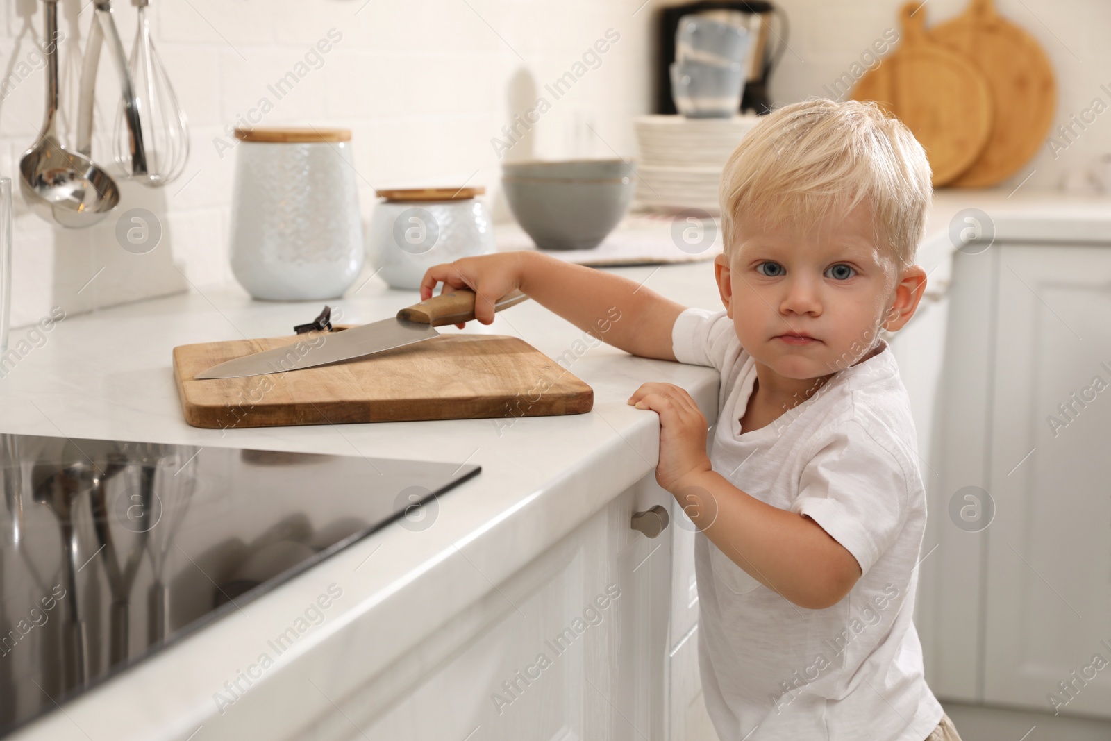 Photo of Curious little boy taking sharp knife from kitchen counter