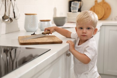 Photo of Curious little boy taking sharp knife from kitchen counter