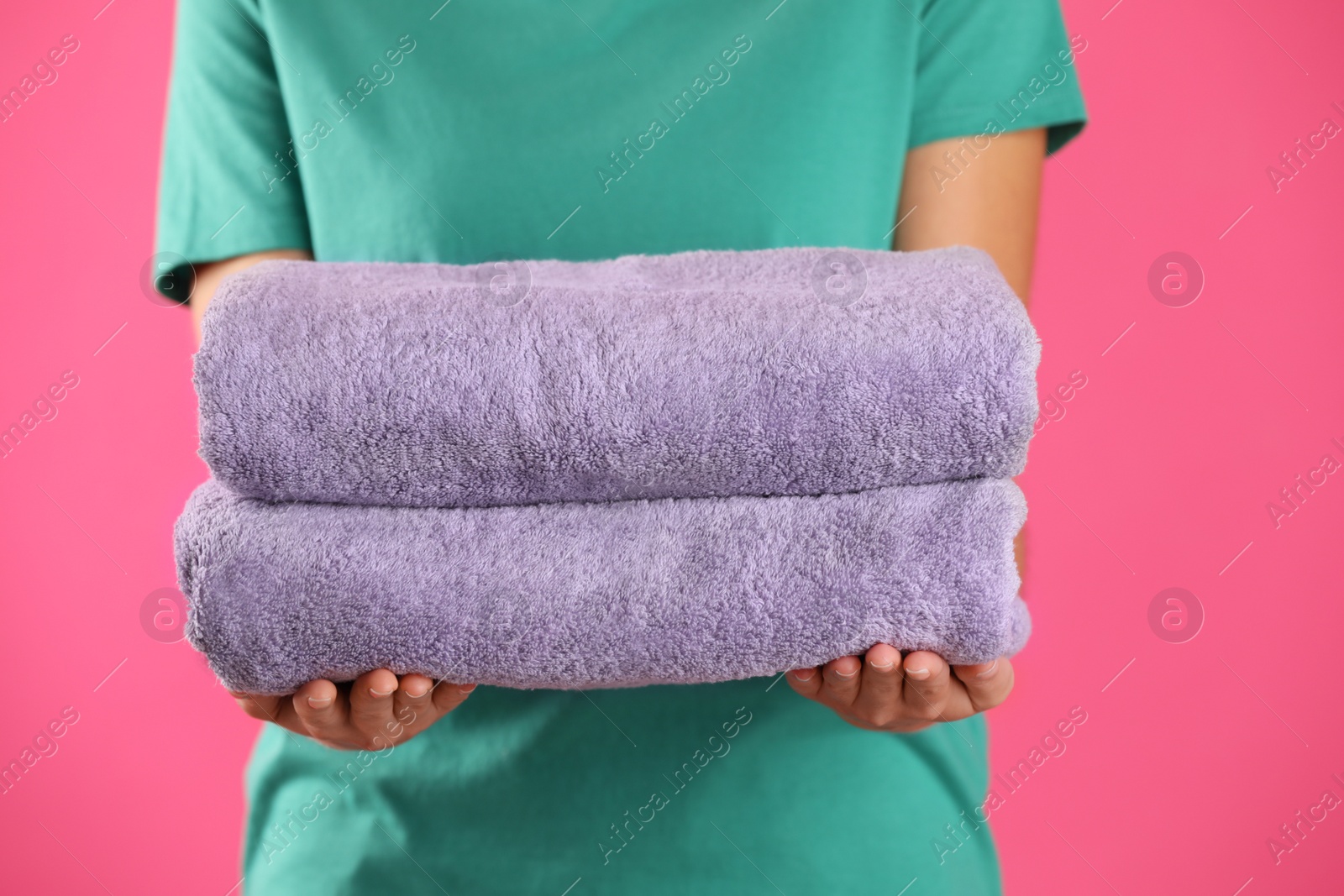 Photo of Woman holding fresh towels on pink background, closeup