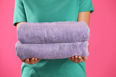 Woman holding fresh towels on pink background, closeup