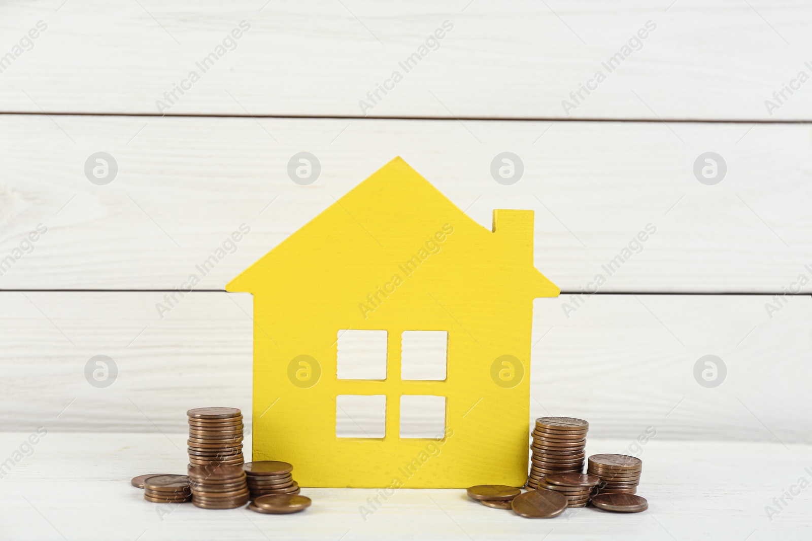 Photo of House model and coins on white wooden table