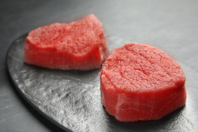 Photo of Fresh raw beef cut on black table, closeup